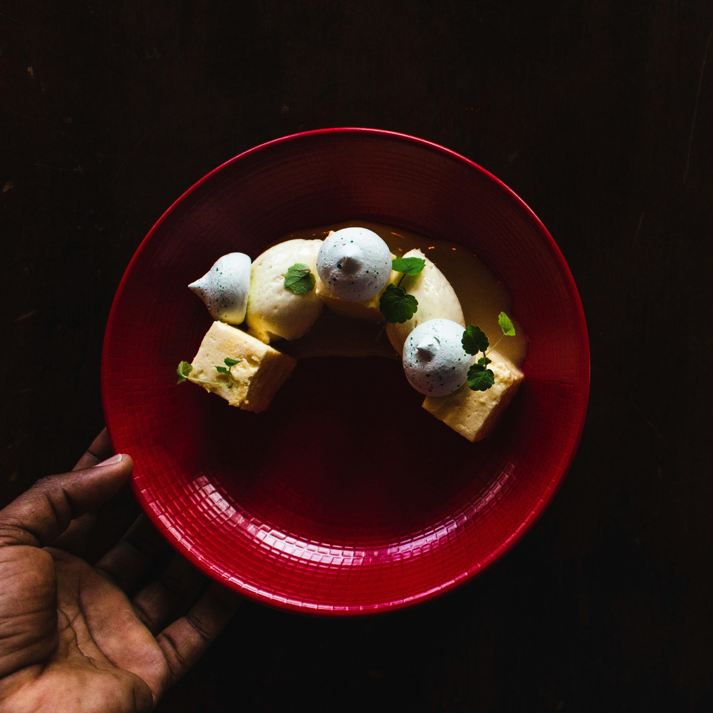 Postre de autor en plato rojo con texturas y cítricos, propuesta creativa del restaurante boutique